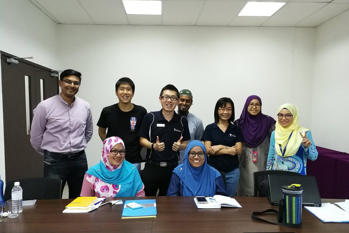 Workshop participants and trainers in a group photo in a meeting room