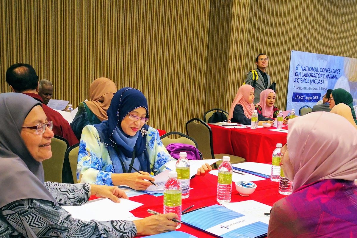 Participants at a red-covered table writing during a session