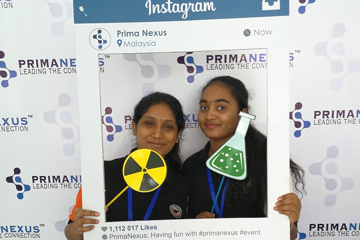 Two delegates pose with a large photo frame at the Prima Nexus photo wall