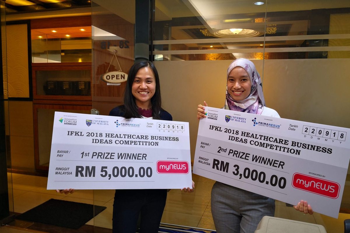 Two competition winners hold large prize cheques for the first and second prizes