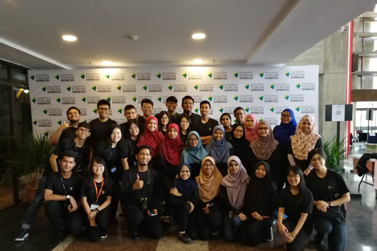 Large group photo of forum participants and organisers in front of the Innovation Forum backdrop at Universiti Malaya