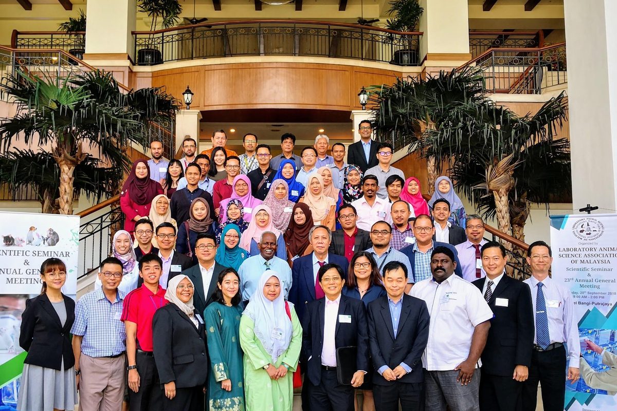 Large group photo of LASAM members and guests on a hotel staircase, between two LASAM banners