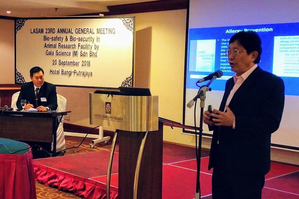 A speaker presents from the stage beside a screen announcing the LASAM 23rd Annual General Meeting