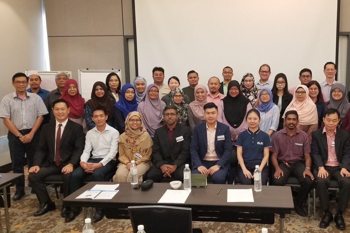 Group photo of LASAM members and speakers, standing and seated, at the front of a hotel meeting room