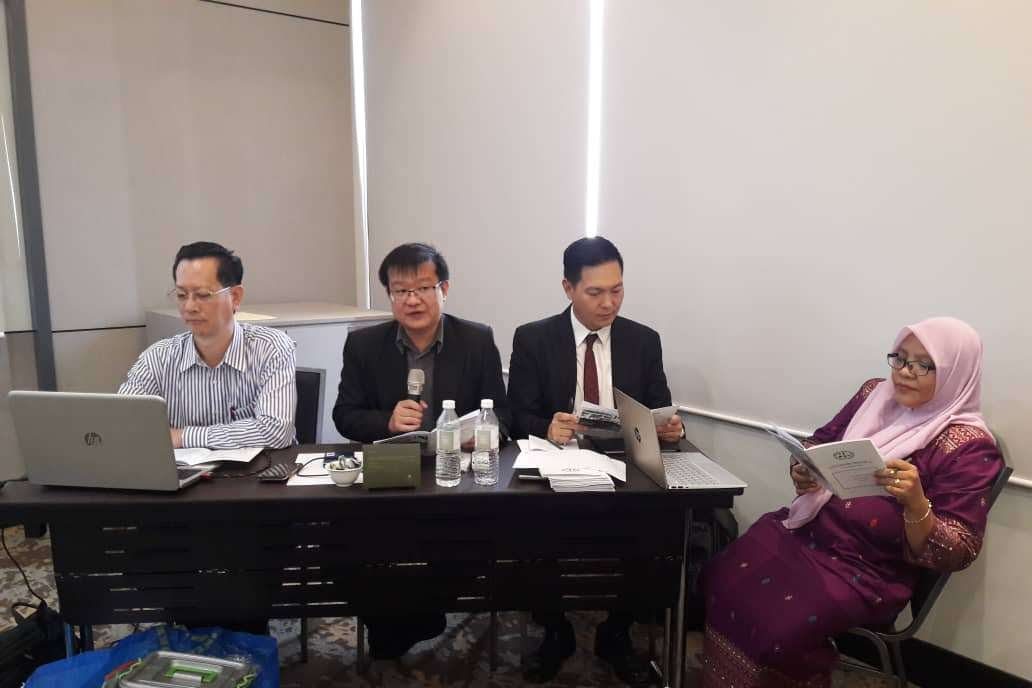 Four people seated at the head table at the front of the meeting room