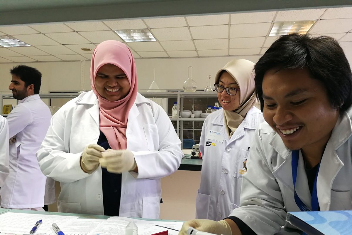 Participants in lab coats smile at the bench
