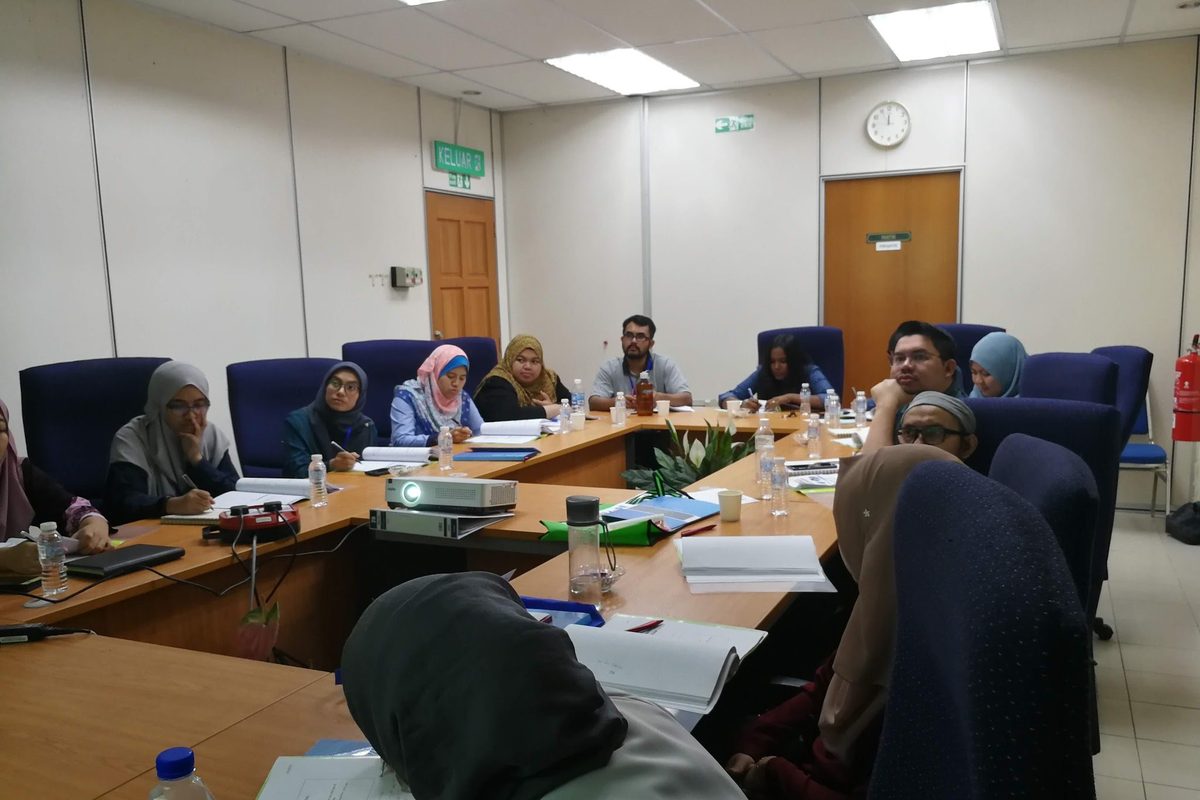 Participants seated around a meeting table during a lecture