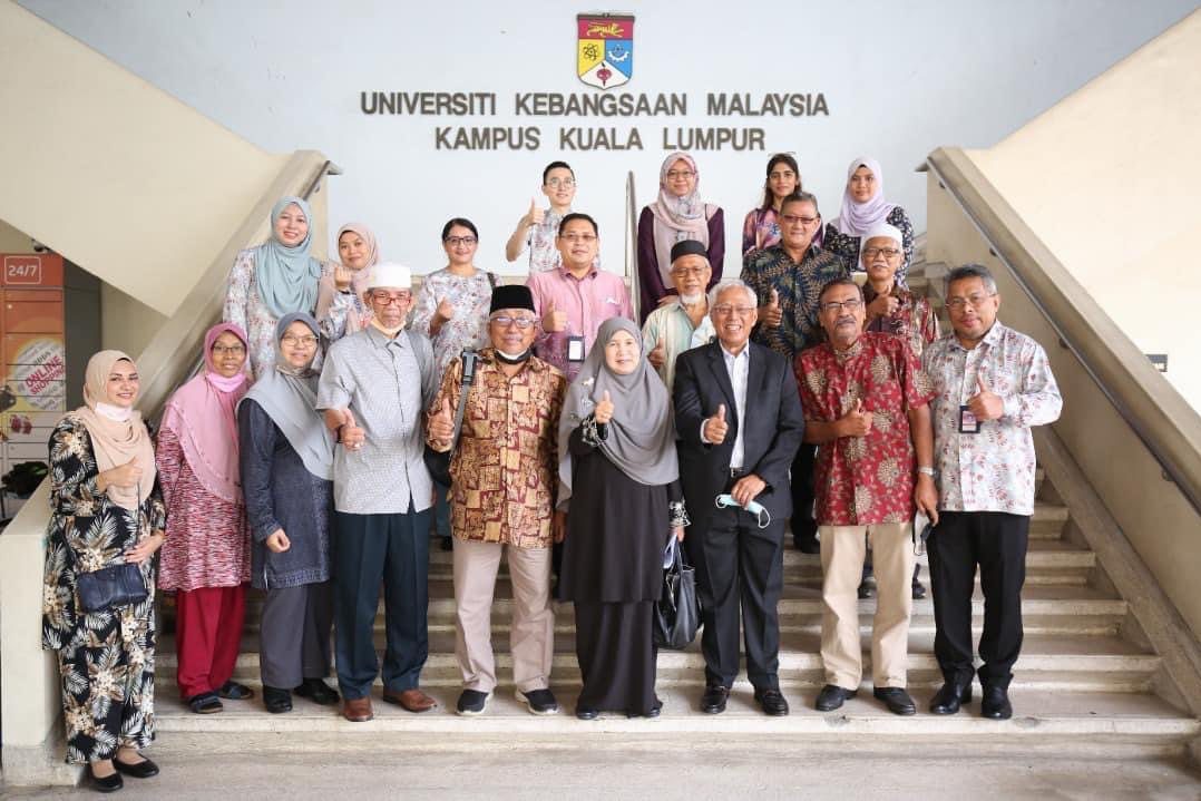 A group of about twenty people, several of them older guests, on the steps below the Universiti Kebangsaan Malaysia Kampus Kuala Lumpur sign