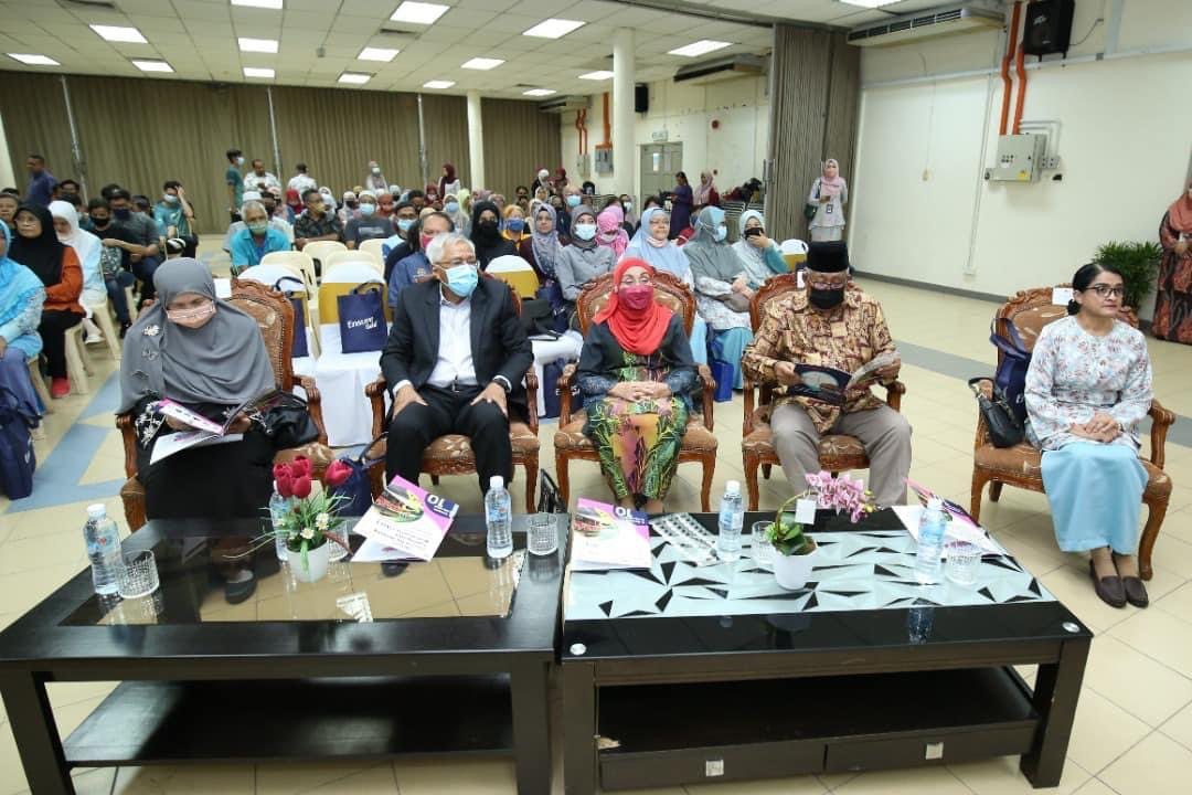 Guests seated in the front row of a hall, with a large audience behind them