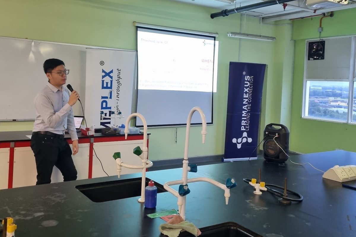 A Prima Nexus banner beside the laboratory bench, with a presenter at the front