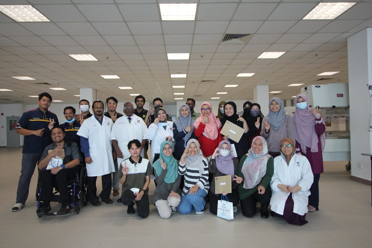 Workshop participants, trainers and staff, some in lab coats, in a group photo in a large laboratory hall