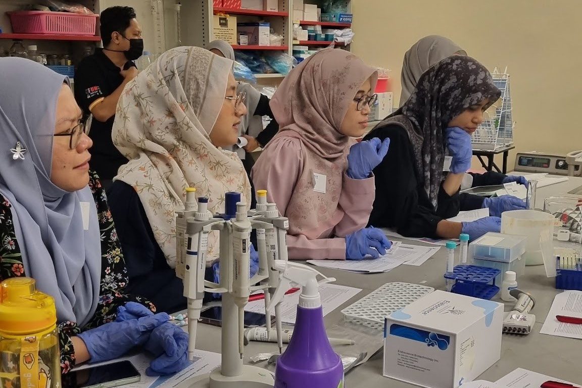 Participants in gloves seated in a row along a laboratory bench, working through the protocol