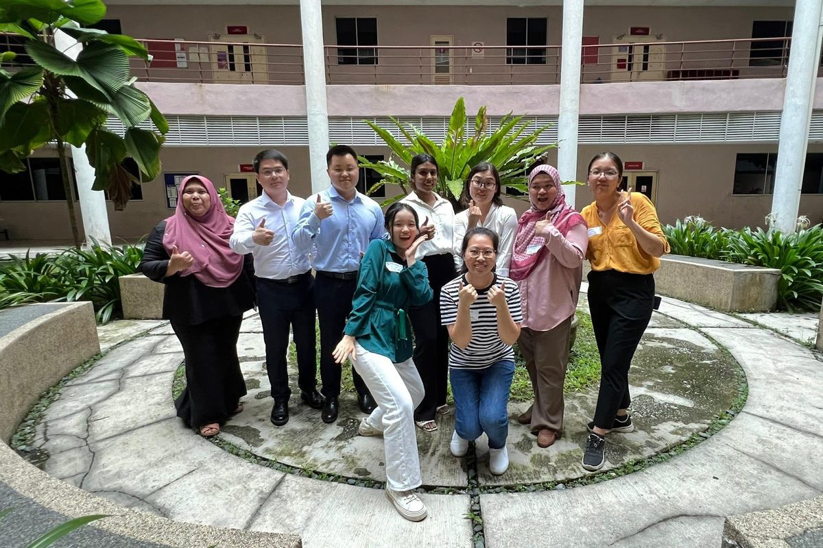 Workshop participants and trainers in a group photo in a courtyard with a round planter