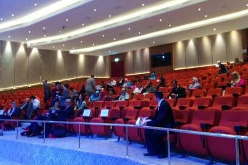 Delegates seated in the red-seat auditorium at Connexion@Nexus, seen from the side aisle