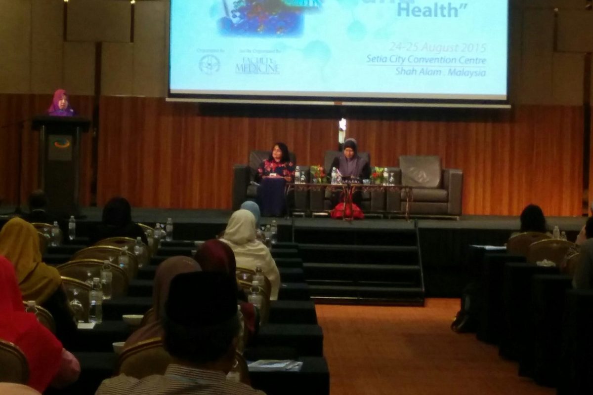 A session on stage, with the meeting's title, theme, dates and venue shown on the screen above