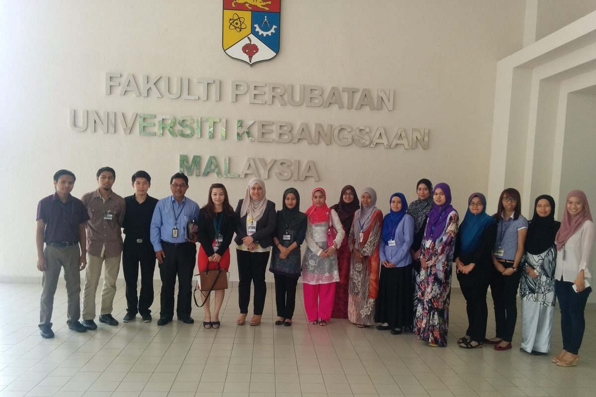 A group of about twenty people standing in a row under the Faculty of Medicine, UKM wall sign