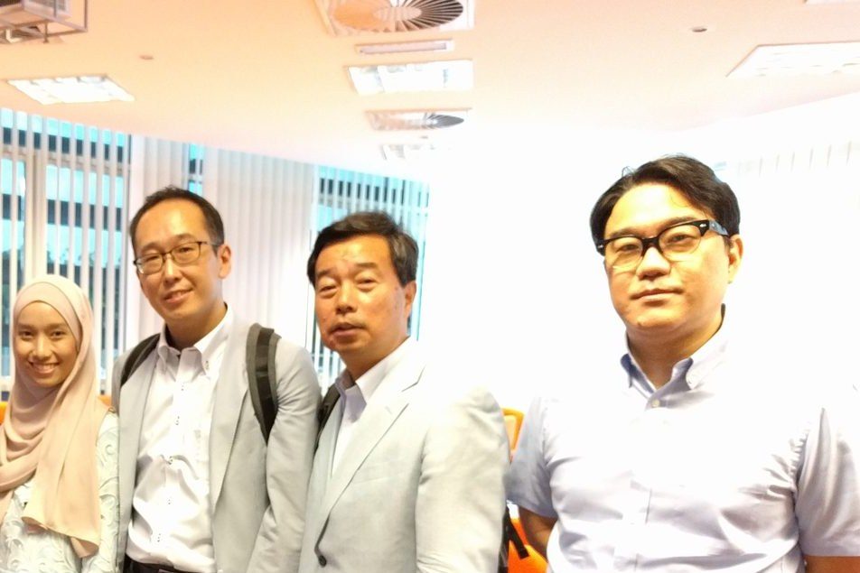 Four people stand together for a photo in the seminar room at UPM at the end of the seminar.