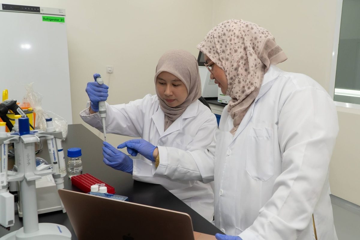 Two scientists in lab coats pipetting samples