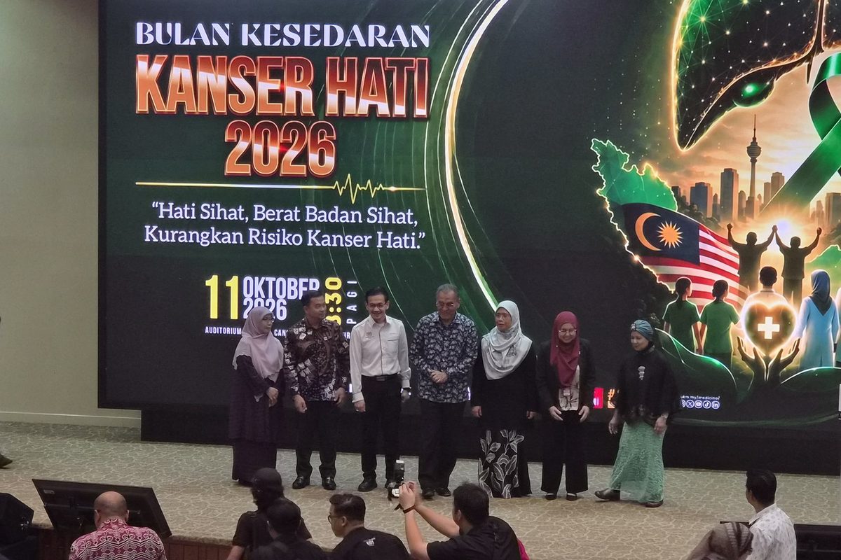 The Minister of Health with guests on stage in front of the Bulan Kesedaran Kanser Hati 2026 screen, as photographers take pictures