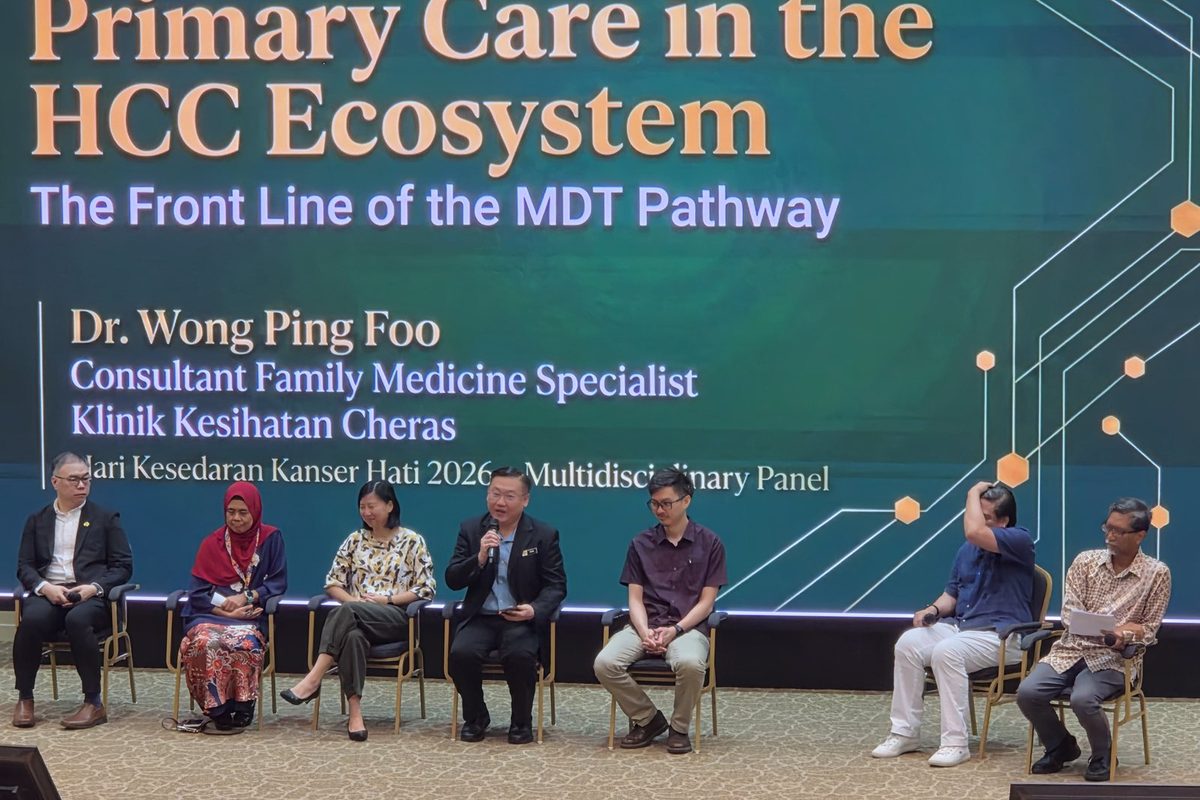 Seven panellists seated on stage under a slide reading Primary Care in the HCC Ecosystem, with one panellist speaking into a microphone