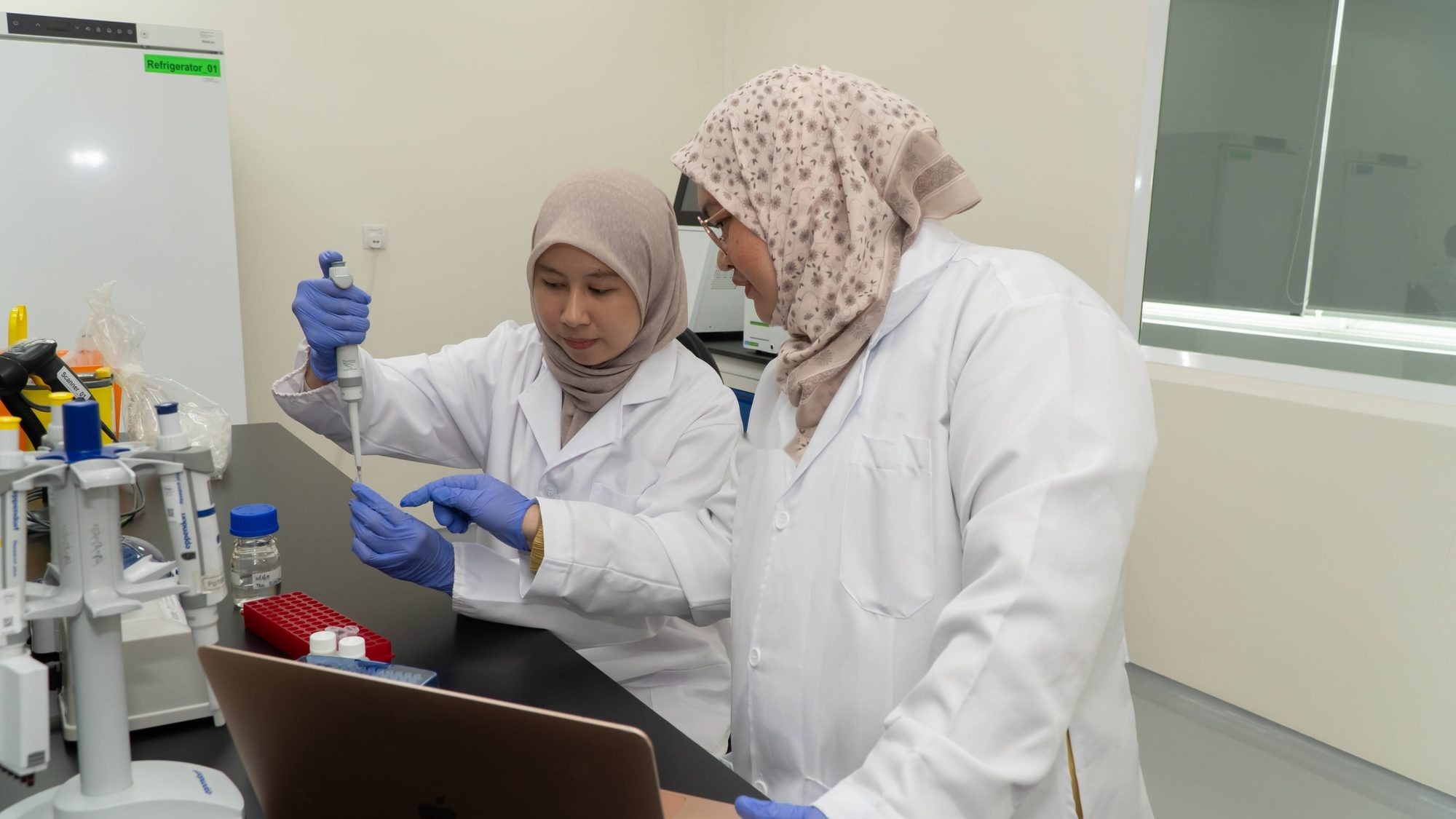 Two scientists in lab coats pipetting samples