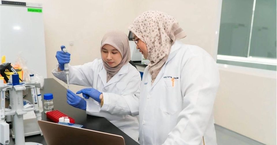 Two researchers in lab coats working at a laboratory bench