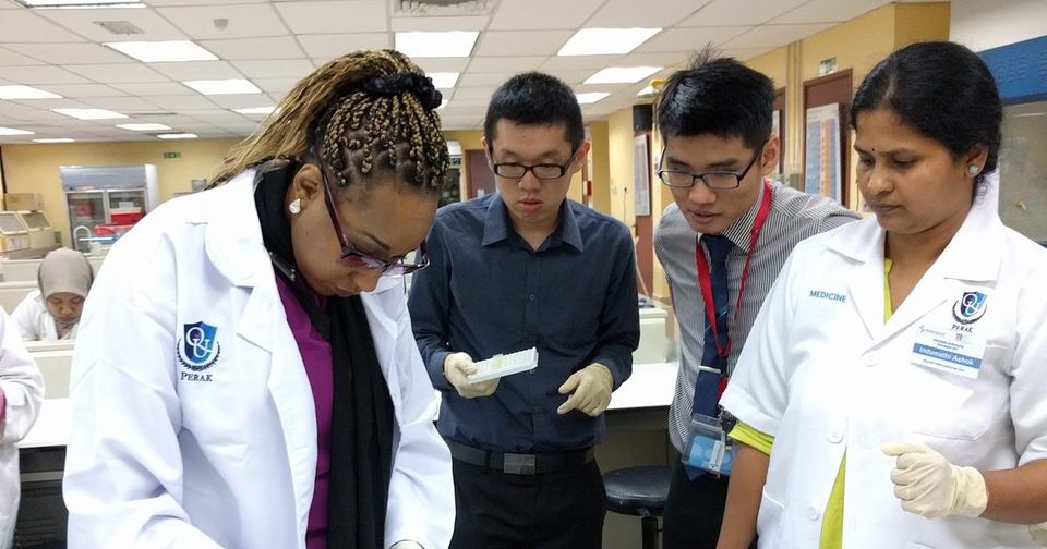 A trainer demonstrates a step at the laboratory bench while participants watch