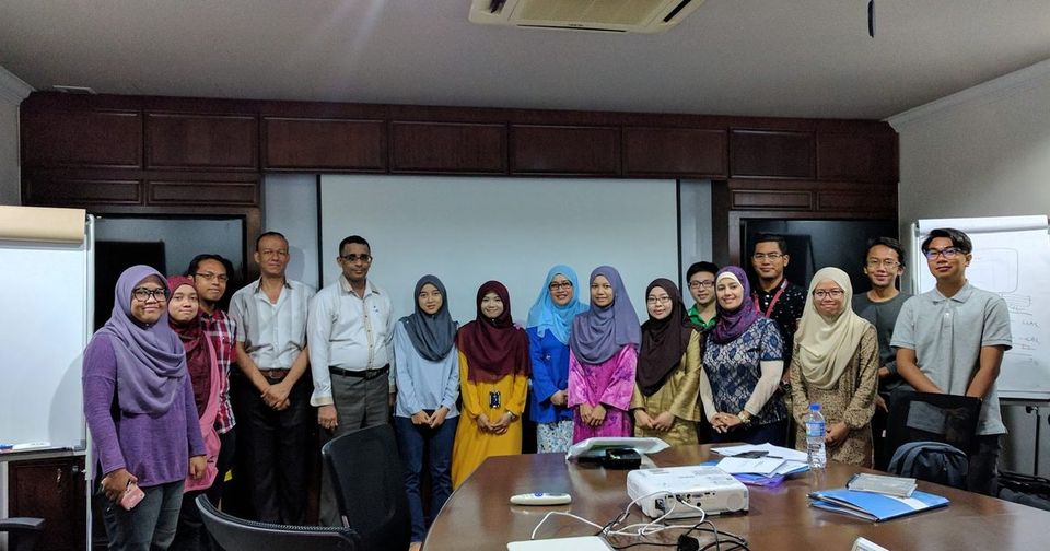 The workshop group standing together for a photo in a meeting room with a long table and a projector
