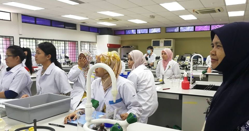 Participants in lab coats at the laboratory benches