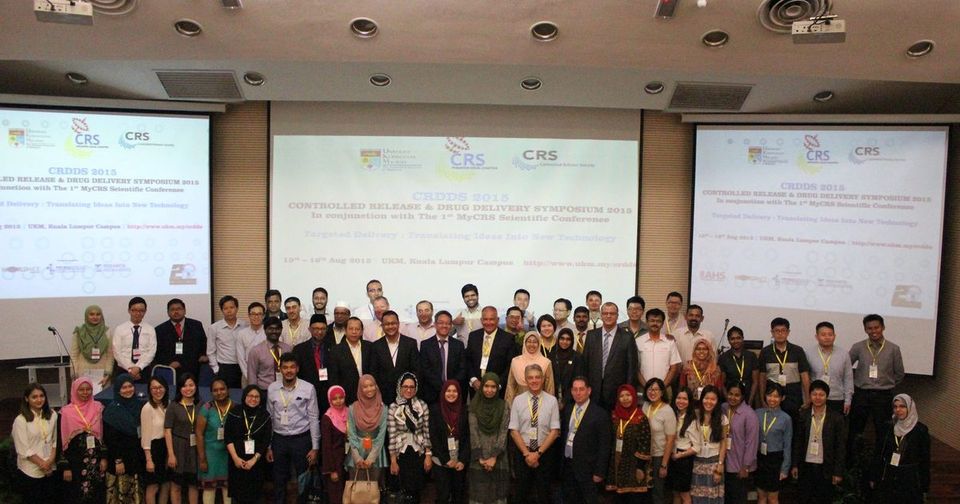 Delegates of CRDDS2015 pose for a group photo in a lecture hall, with the symposium title on three screens
