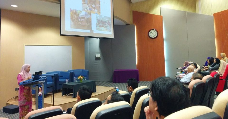 A speaker at the lectern presents a slide titled Post Flood to an audience in a university auditorium