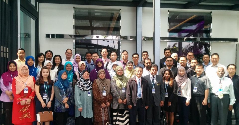 Group photo of the seminar participants standing in rows under a glass canopy at Le Meridien Kuala Lumpur
