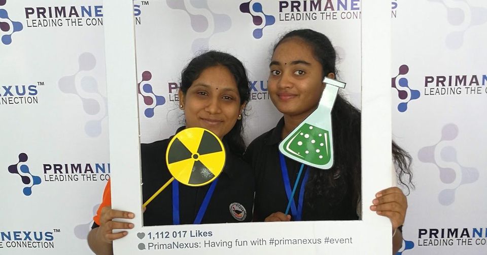 Two delegates pose with a large photo frame and props at the Prima Nexus photo wall
