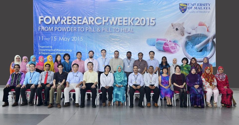 A large group seated and standing in two rows in front of the FOM Research Week 2015 backdrop