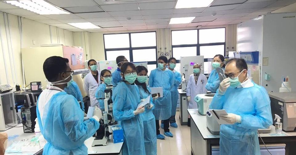 Workshop participants in blue gowns, masks and shoe covers in the tissue culture laboratory