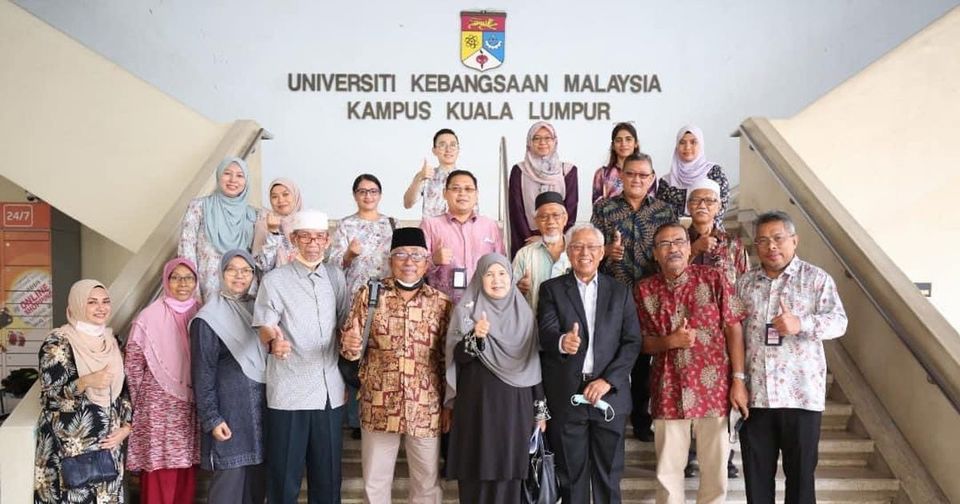 A group of about twenty people, several of them older guests, on the steps below the Universiti Kebangsaan Malaysia Kampus Kuala Lumpur sign