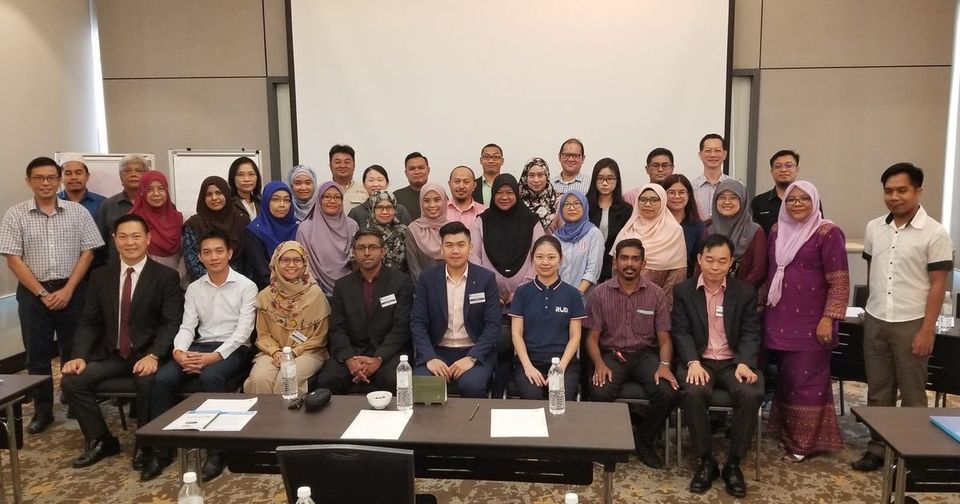 Group photo of LASAM members and speakers, standing and seated, at the front of a hotel meeting room
