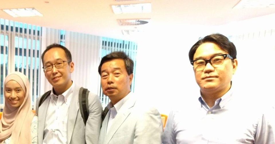 Four people stand together for a photo in the seminar room at UPM at the end of the seminar.