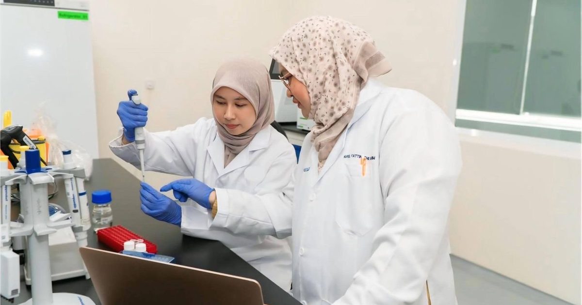 Two researchers in lab coats working at a laboratory bench