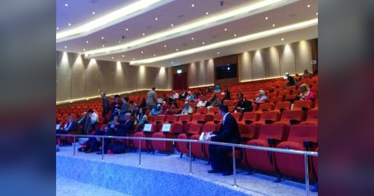 Delegates seated in the red-seat auditorium at Connexion@Nexus, seen from the side aisle