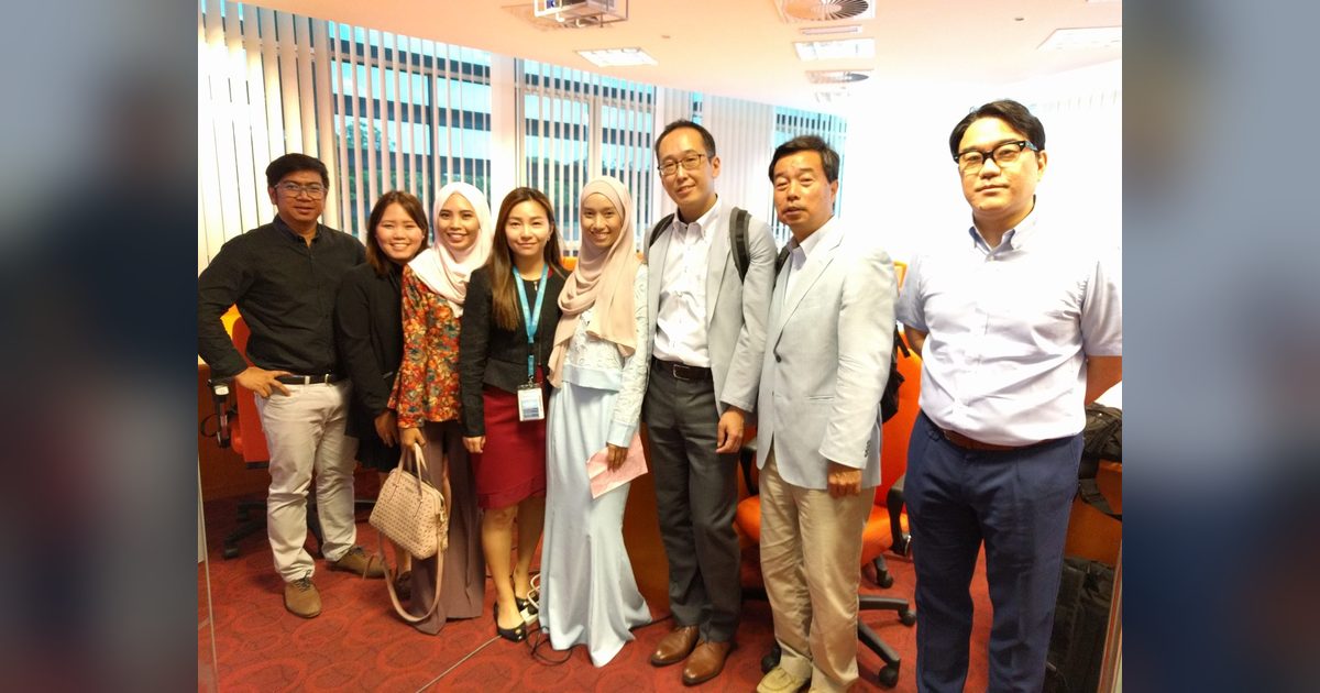 Eight people stand in a row for a group photo in the seminar room at UPM at the end of the seminar.